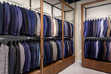 Racks with different men's suits in a men's clothing boutique. Modern fashionable brand interior of men clothing shop store.