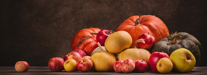 Autumn harvest, happy Thanksgiving day, Halloween. Festive still life with pumpkins and apples on dark  brown background with copy space.