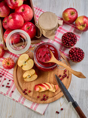 Wooden spoon with appetizing lingonberry and apple jam, jar of jam, fresh fruits and berries on light wooden table. Home canning