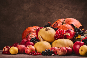 Autumn harvest, happy Thanksgiving day, Halloween. Still life with pumpkins, berries, apples on dark  brown background with copy space.