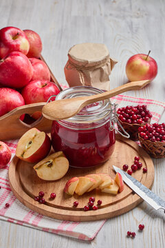 Glass jar of homemade jam from lingonberries and  red apples. Still life with fresh fruit and berries on light wooden table.