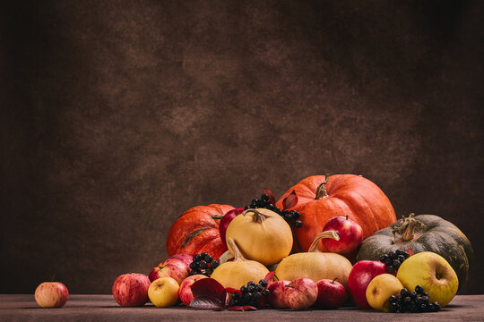 Autumn harvest, happy Thanksgiving day, Halloween. Festive still life with pumpkins and apples on dark  brown background with copy space.