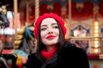 Obraz premium beautiful girl in a red beret and mittens in winter on New Year's street.