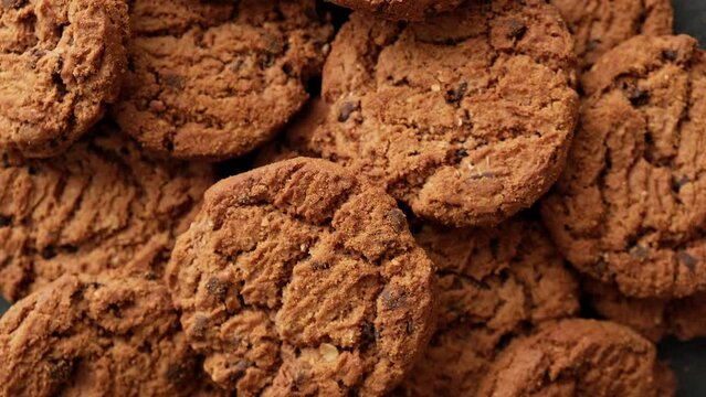 Pile of whole meal cookies. Fresh oatmeal cookies rotating. Food concept. Homemade cookies with chocolate. Close-up in 4K, UHD