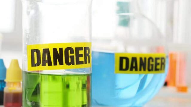Bottles with chemical liquids green and blue corol with danger warning in labaratory. Medical equipment in lab