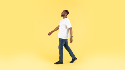 Fototapeta na wymiar Carefree African American Man Walking Smiling Looking Aside, Yellow Background
