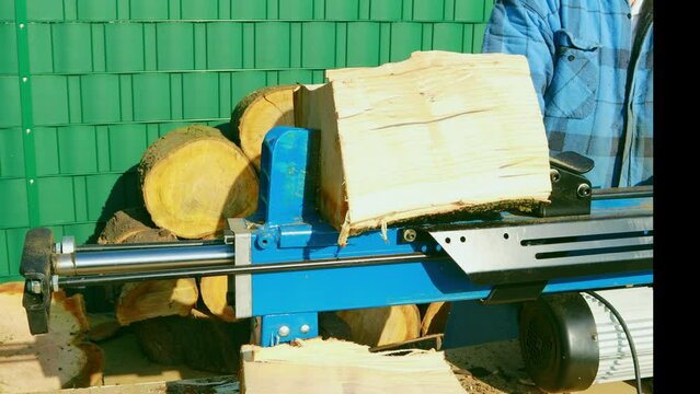 Firewood is chopped by a man on a wood splitter. Preparations for the winter for the fireplace. The concept of heat, energy, heating, europe, eco-friendly, gas,industry, environment, countryside.