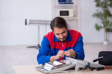 Young male repairman repairing heater