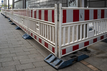 warning fencing around renovations on a pedestrian street near the road next to a building