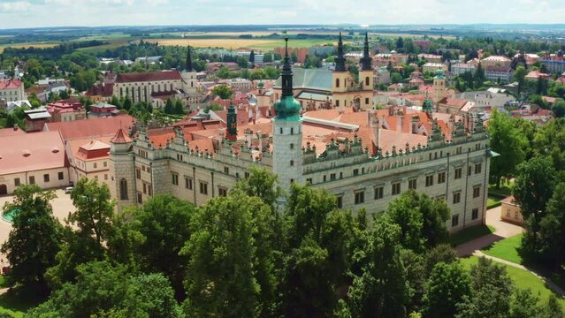 Green trees grow near castle with pointed terracotta roof in Litomysl. Ancient architecture of Czeck Republic included in UNESCO aerial view