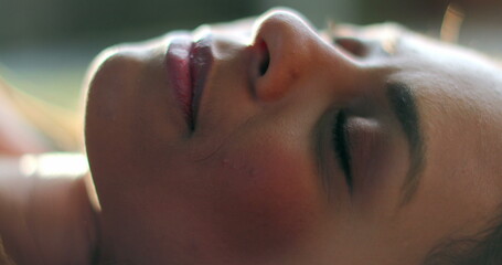 Fototapeta premium Woman opening eyes lied on grass outside daydreaming, relaxed girl