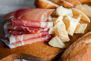 Wooden board with cheese and ham. Board with jamon and cheese. Aperitif on the board. Jamon with bruschetta and parmesan.Delicious appetizer for wine.Italian appetizer. Jamon and salami with cheese.