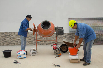 Two construction workers at work on a construction site preparing concrete with a concrete mixer....