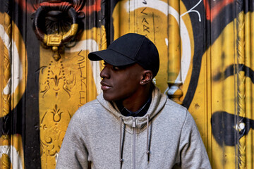 Man in black cap against graffiti.