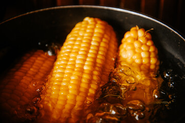 Orange juicy corn is boiled in water with salt. Corn in boiling water in a saucepan. Healthy food and vegetables.