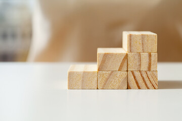Hand arranging wood cube stacking as step stair.