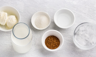 Obraz na płótnie Canvas Ingredients for dalgona coffee. Instant coffee, milk, ice cream, water, ice and sugar. Light gray textured background
