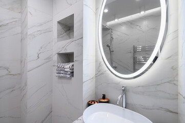 White bathroom interior with marble tiles on the walls