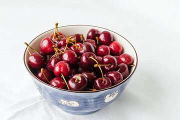 Sweet cherries with drops of water in the bowl on white background closeup. Cherry organic berries harvest - healthy eating and food concept