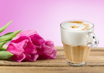 Fresh flowers and coffee cup on pastel background.