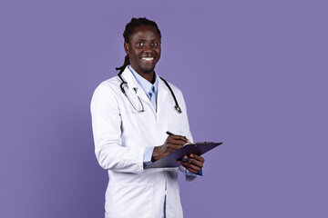 Portrait of friendly young african american doctor on purple - obrazy, fototapety, plakaty