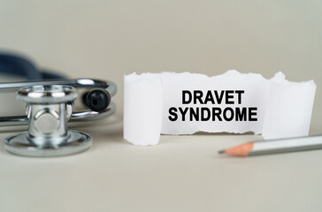 On a gray background, a stethoscope, a pencil and a paper plate with the inscription - Dravet...
