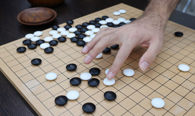 Young people move black and white stones while playing go