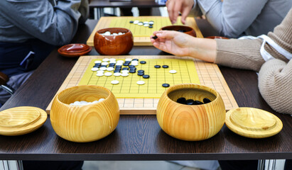 Young people move black and white stones while playing go