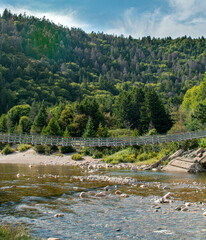 suspension bridge over a river in the mountains.