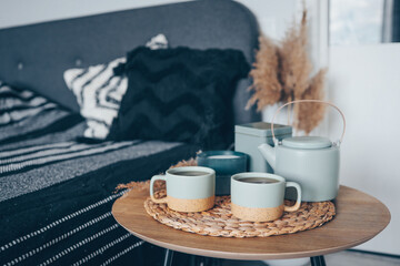 Bedroom decorative objects on the bed in cozy vintage bedroom. Two cups of tea and a ceramic teapot. Home decoration concept