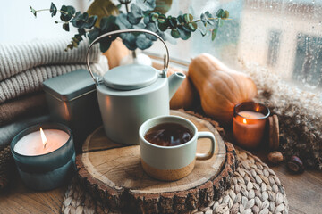 Beautiful autumn composition with burning candles and cup of tea on window sill