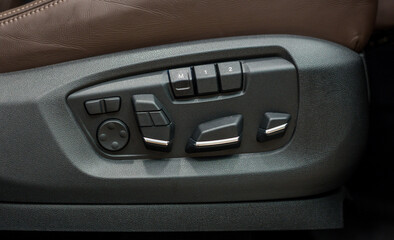 Seat adjustment control unit in a new luxury car. Seat of modern car with brown leather and seat control unit close-up. Interior of modern luxury car.