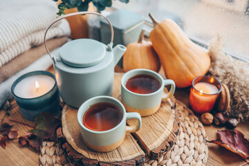 Beautiful autumn composition with burning candles and cup of tea on window sill