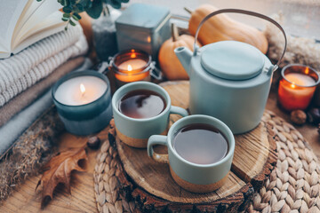Fototapeta na wymiar Beautiful autumn composition with burning candles and cup of tea on window sill