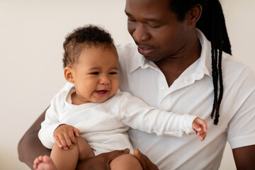 Portrait Of Little Black Baby Crying In Father's Arms