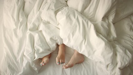 Only legs in the frame. A couple in love is having fun in bed, twisting their feet in different directions. Marriage, family, love. Marriage, family, love, sex concept. Morning two in bed 4k
