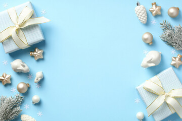 Christmas flat lay composition with present boxes and beige decorations on pastel blue background.