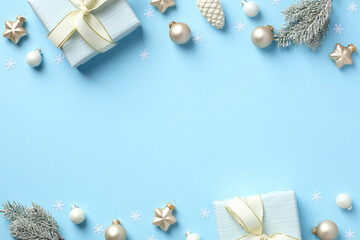 Winter holidays background with gift boxes, fir branches in snow, baubles on pastel blue table. Christmas card design, banner design.