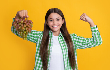 cheerful child with grapes bunch on yellow background. diet