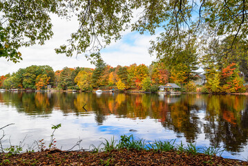 Wooden jetties along the forested bank of a river on a cloudy autumn day. Beautiful autumn colours and reflection in water.
