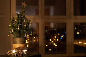  homemade Christmas decor. Small Christmas tree by candles and golden pine cones