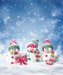 Merry Christmas and happy New Year greeting card with copy space. Three snowmen standing in snow. 