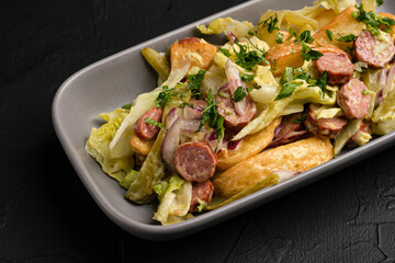 Salad with sausages, fresh salad with sausages and on a black background