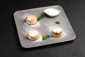 Cheesecakes, cheesecakes with sour cream for breakfast on a black background