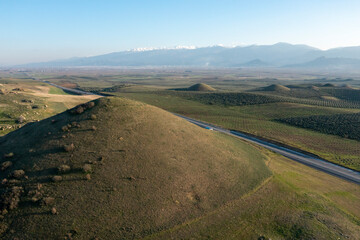 Aerial Photography, drone view from tumulus hills and road and fields with low light 
