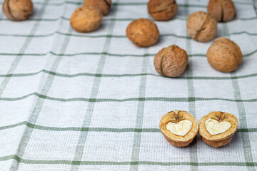 A heart-shaped cracked nut in the foreground, isolated on a beautiful white towel. Half a walnut. Background for the menu. Space for text