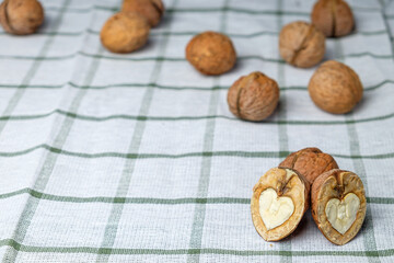 A heart-shaped cracked nut in the foreground, isolated on a beautiful white towel. Half a walnut. Background for the menu. Space for text