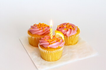 3 colorful strawberry lemonaide flavor cupcakes with candle on white background