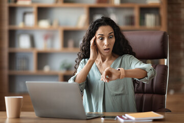 Stressed young businesswoman looking at watch, got late