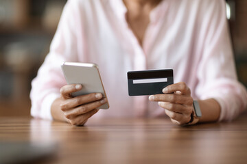 Cropped of woman holding cell phone and credit card